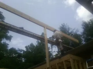 Carpenter setting a ridge beam over a new addition frame — Ice Dam Removal by Roofing Brothers in Noonan