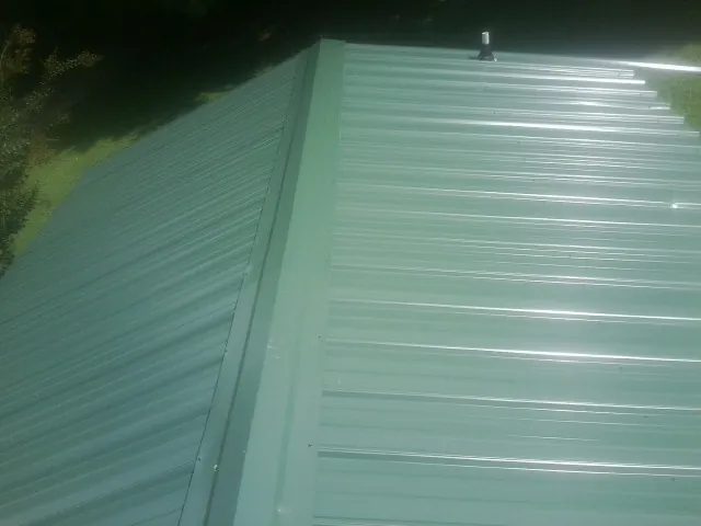 New green metal panels meeting at the ridge of a roof — Flat Roof Repair work by our crew in Noonan