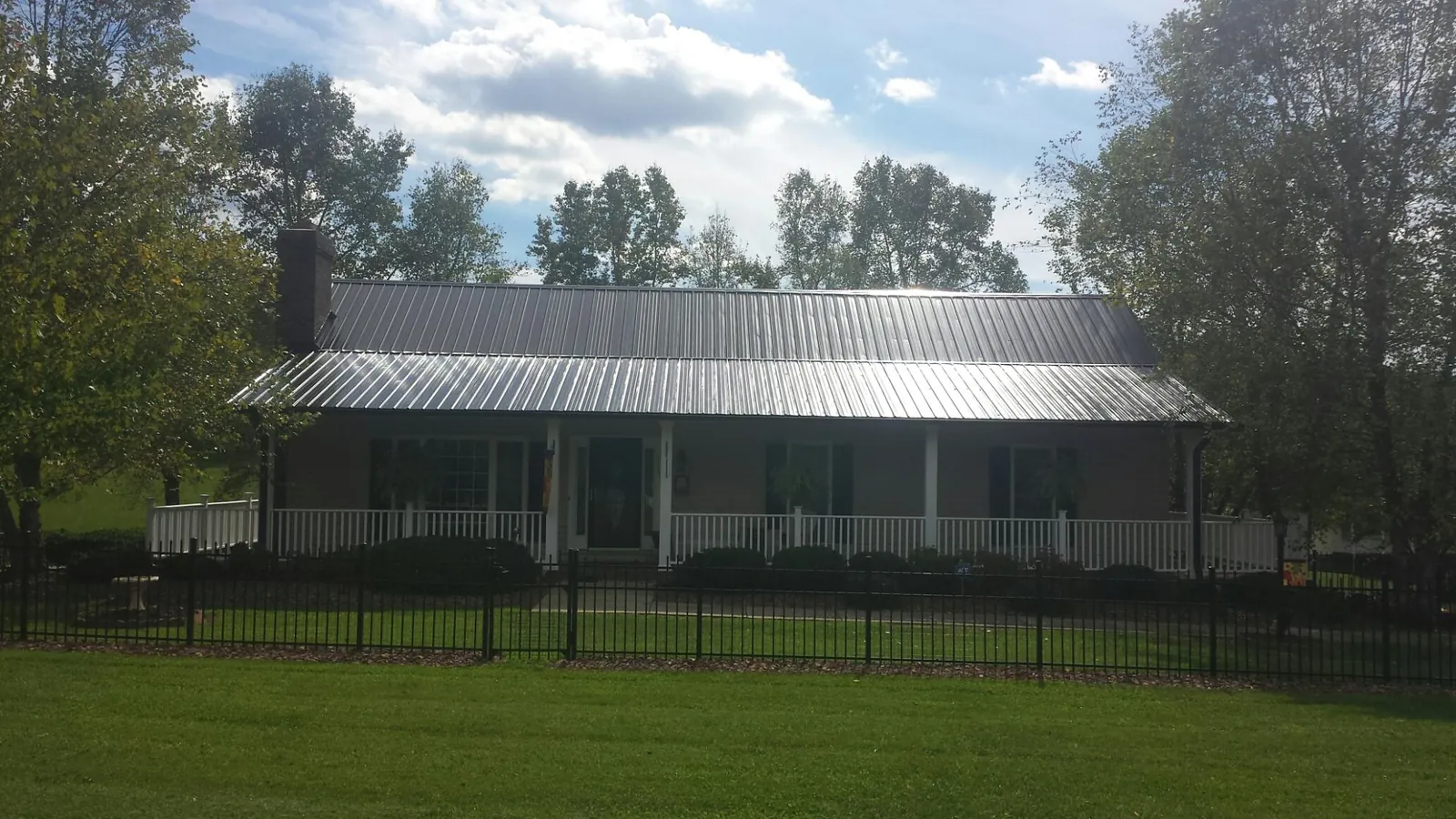 Gray metal roof on a brick ranch with a full width front porch — Gutter Guard Installation work by our crew in Noonan