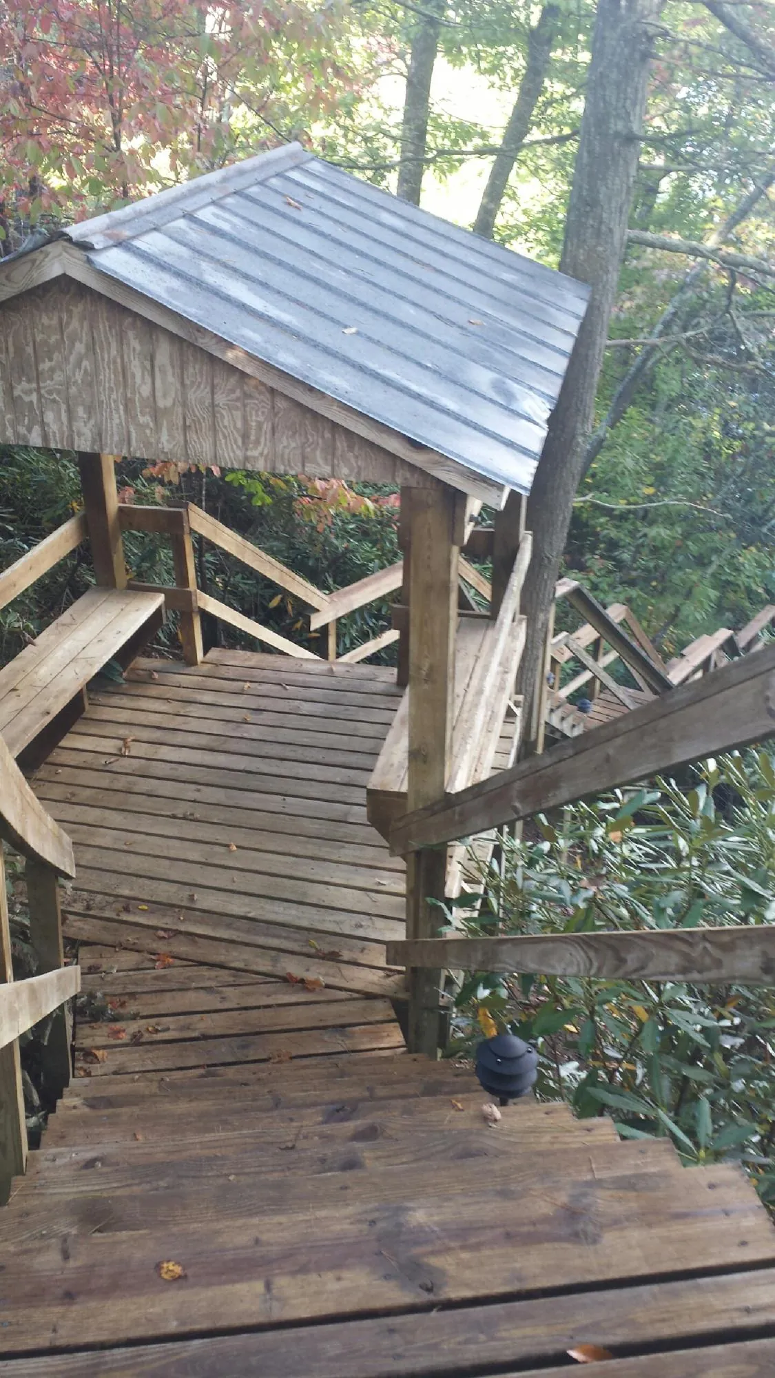 Metal roofed shelter over wooden steps on a wooded walkway — Skylight Repair & Installation work by our crew in Noonan
