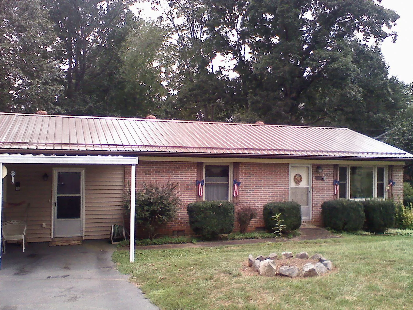 Bronze metal roof and carport on a brick ranch home — Roof Repair work by our crew in Noonan