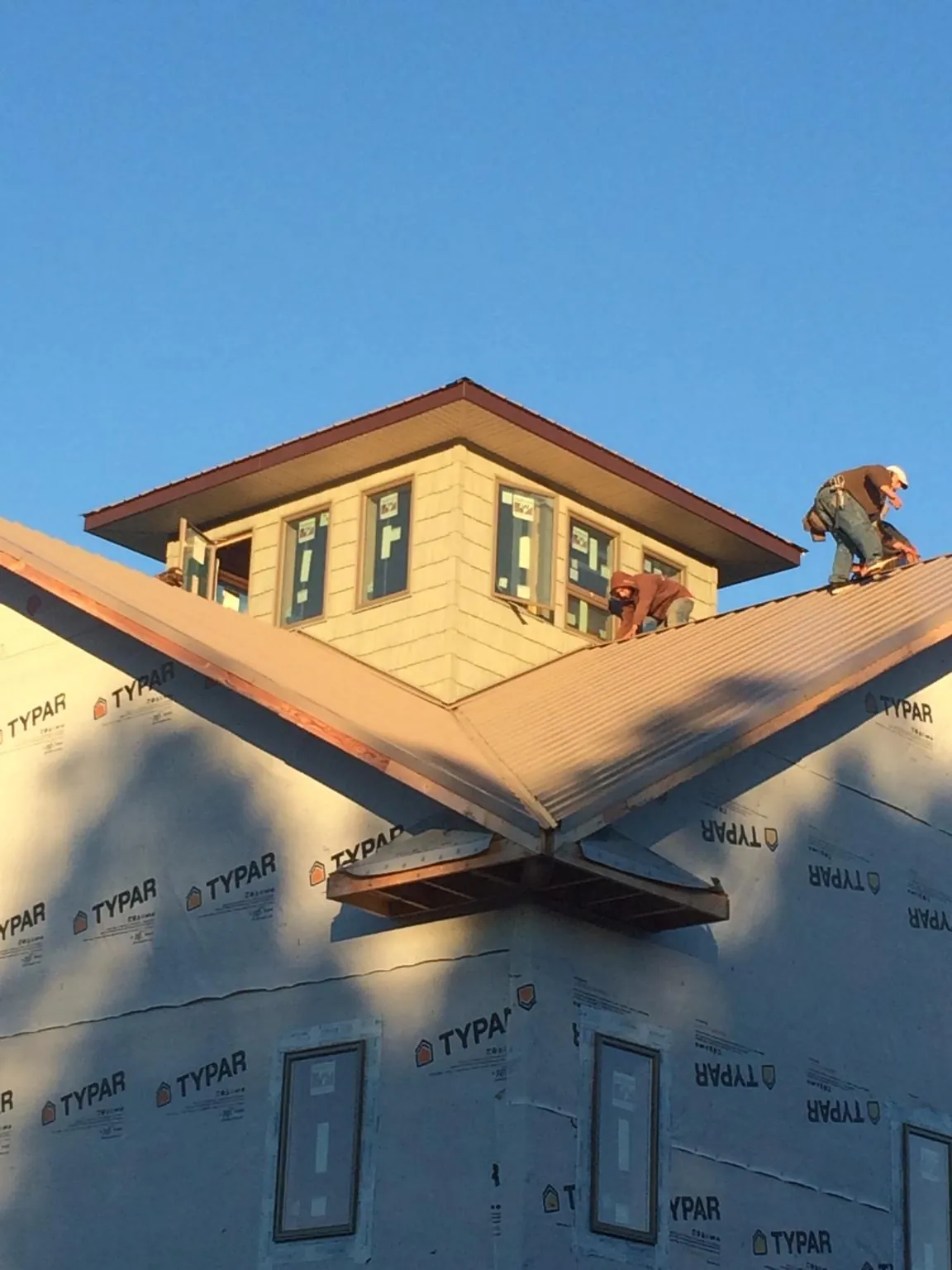 Roofers working around a rooftop cupola on a new metal roof at sunset — Roof Waterproofing in Noonan by Roofing Brothers